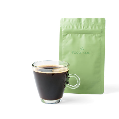 Glass of black coffee next to a green 'Food Force' coffee package on a white background